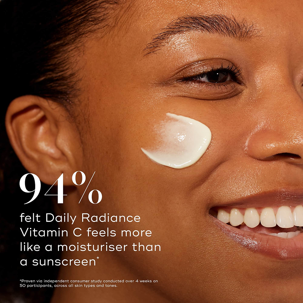 Close-up profile of a smiling model with a smear of cream on her cheek. Bold text states that 94% felt Daily Radiance Vitamin C feels more like a moisturiser than a sunscreen.