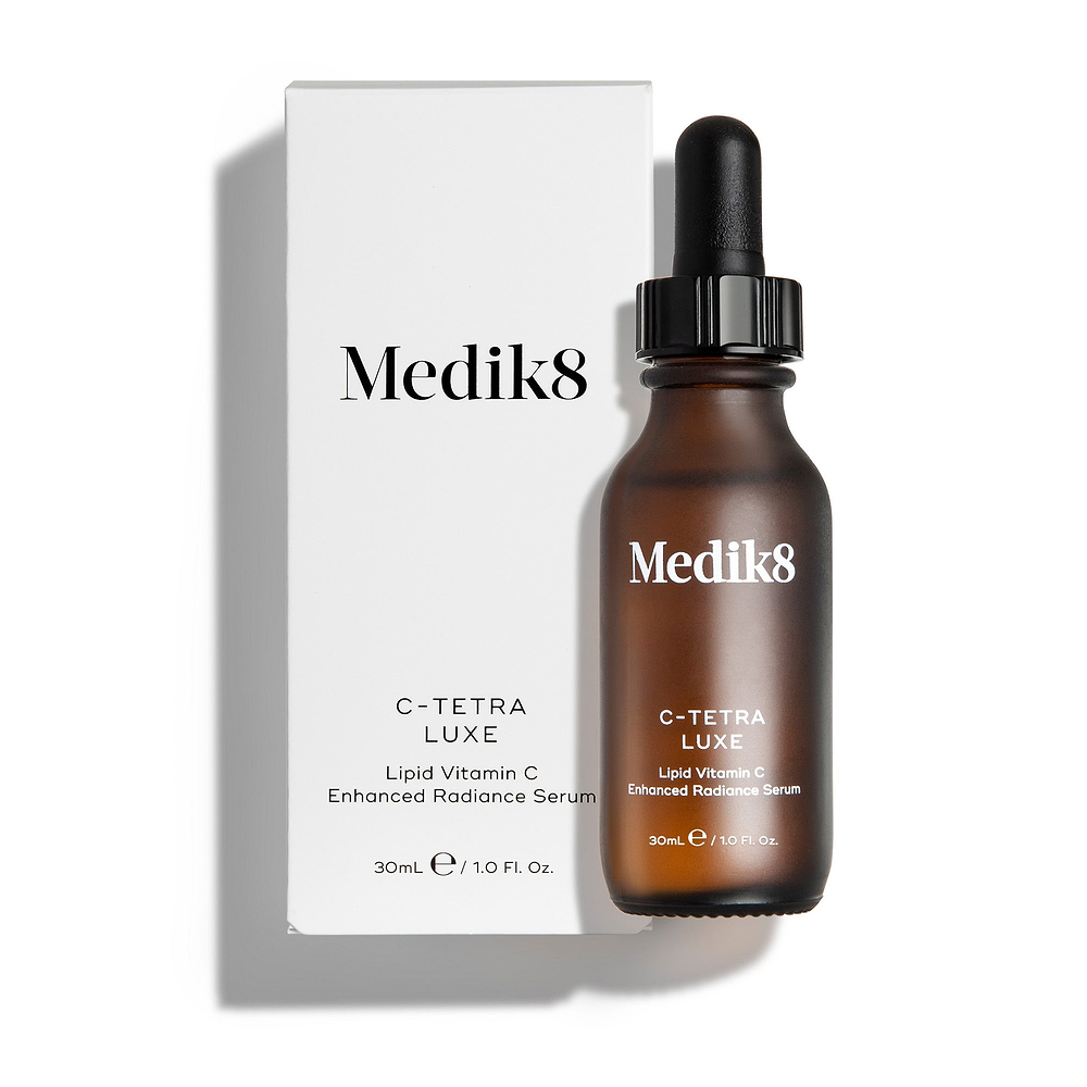 Medik8 C-Tetra Luxe serum bottle and its white cardboard carton displayed on a clean white background with soft shadows. The amber glass bottle and white box both feature the Medik8 logo and identify the product as "C-TETRA LUXE Lipid Vitamin C Enhanced Radiance Serum" in a 30mL size.