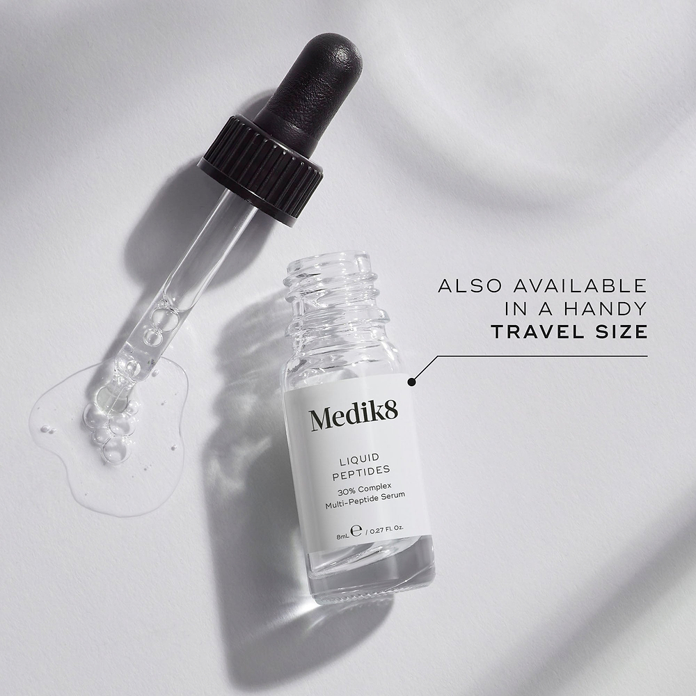 A small clear glass bottle (8mL) of Medik8 Liquid Peptides serum, with its dropper resting beside it. Text indicates it's "ALSO AVAILABLE IN A HANDY TRAVEL SIZE.