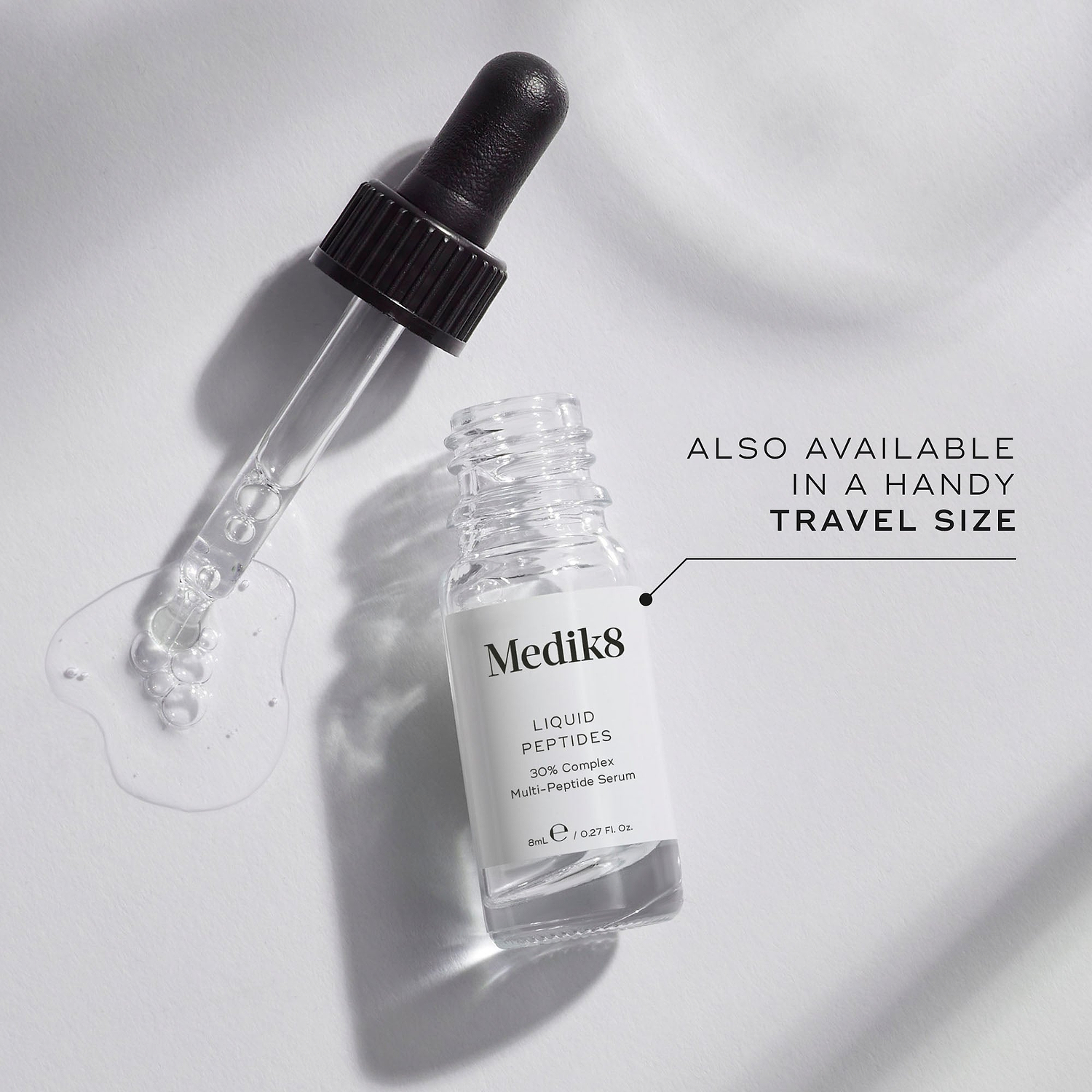A small clear glass bottle (8mL) of Medik8 Liquid Peptides serum, with its dropper resting beside it. Text indicates it's "ALSO AVAILABLE IN A HANDY TRAVEL SIZE.