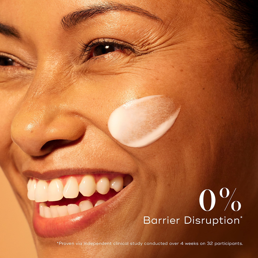 Smiling woman with radiant skin and a swipe of Medik8 C-Tetra Advanced serum on her cheek, emphasising 0% barrier disruption for gentle yet effective brightening.