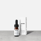 Medik8 Intelligent Retinol 6TR Travel Sized serum bottle stands next to its matching white product carton on a grey textured surface against a neutral background. Text on the 4mL bottle identifies it as a "Supercharged 0.6% Vitamin A Serum."
