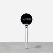 A silver Medik8 metal tube squeezer standing upright on a grey surface. The circular head features the "Medik8" logo, designed to help dispense product efficiently.